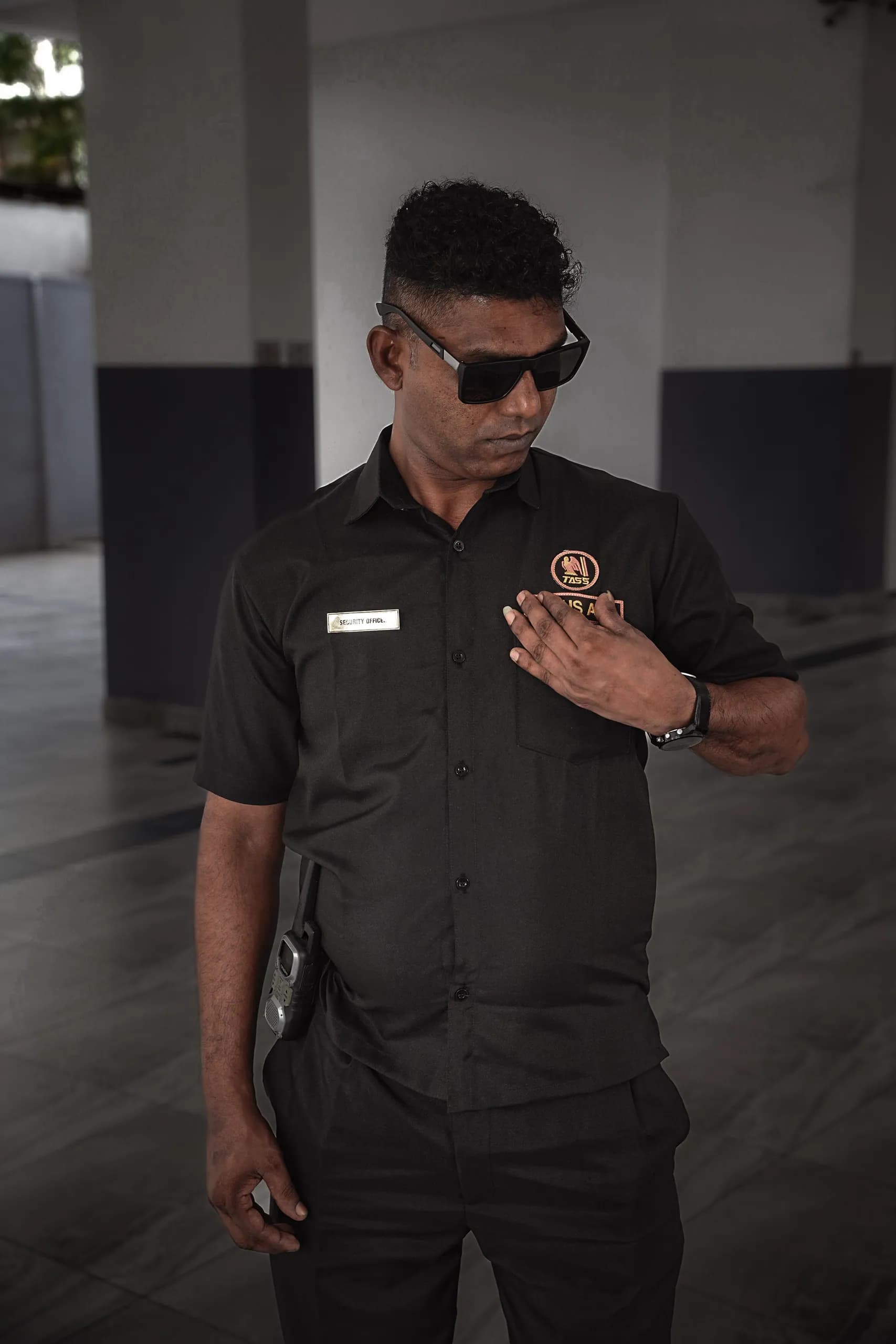 Trans Asia officer in the company black uniform, hand on the crest, with name tape and radio
